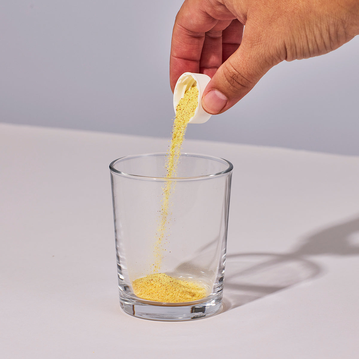 image of person pouring on cap of Isotonix Vision with Lutein powder into a glass