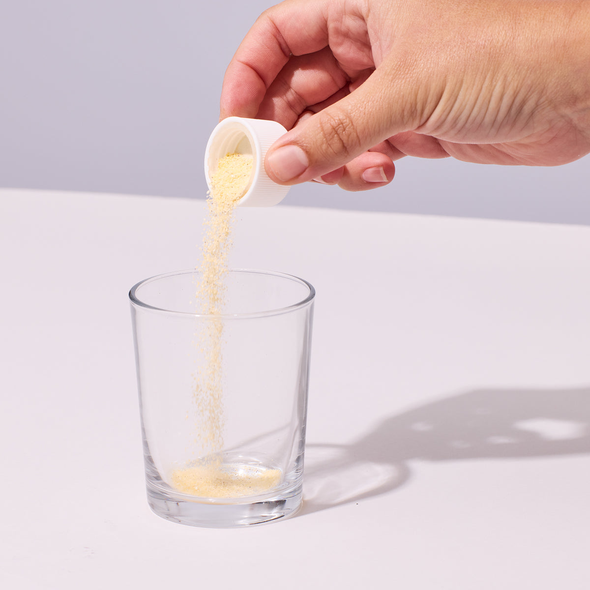 Image of person pouring Isotonix Multivitamin into a clear glass of water