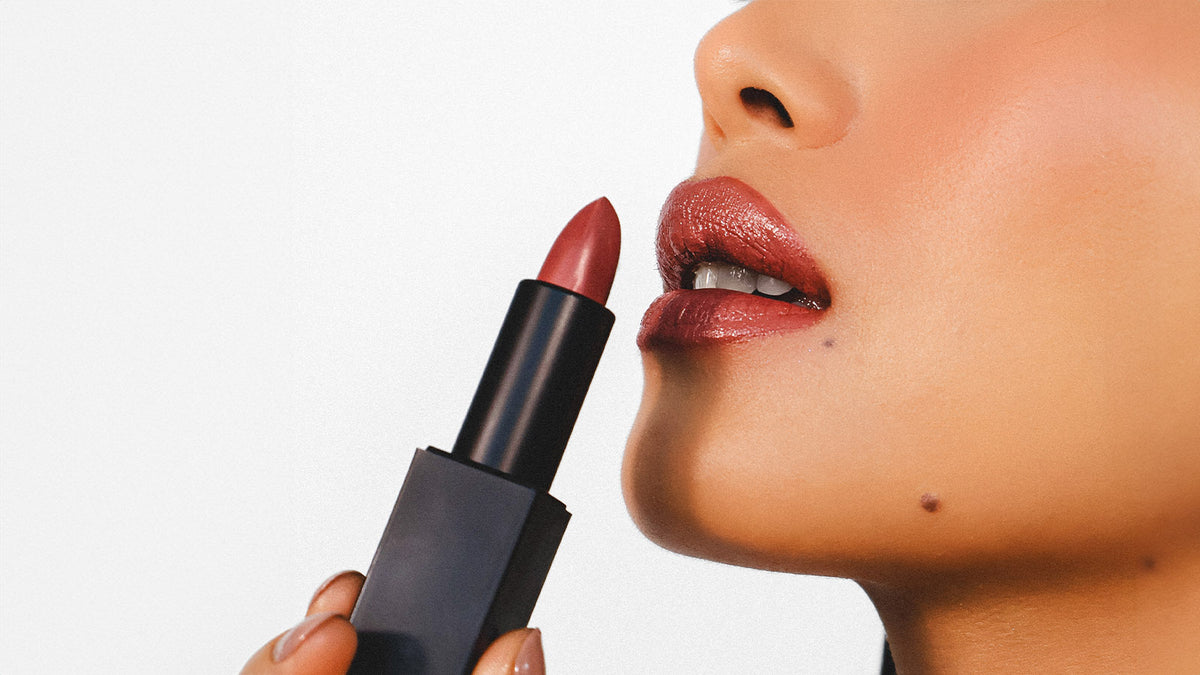 a women is holding a lipstick next to the lip