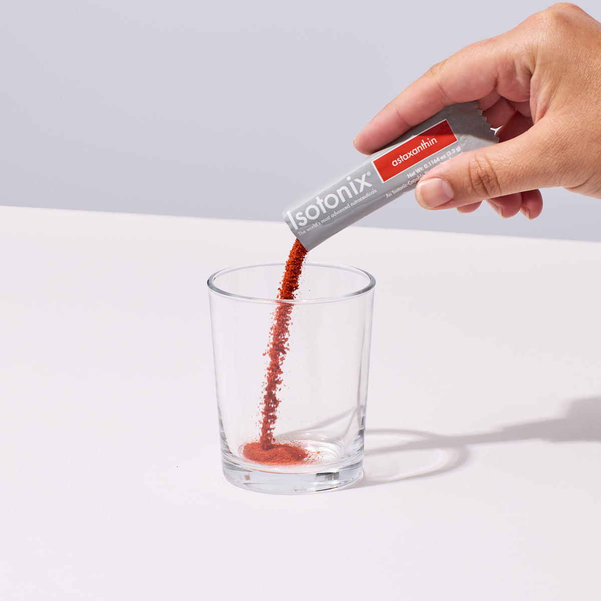 image of someone's hand pouring a serving of Isotonix Astaxanthin into a glass