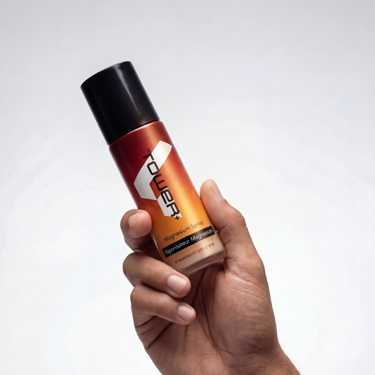 A hand is holding the Magnesium Spray bottle