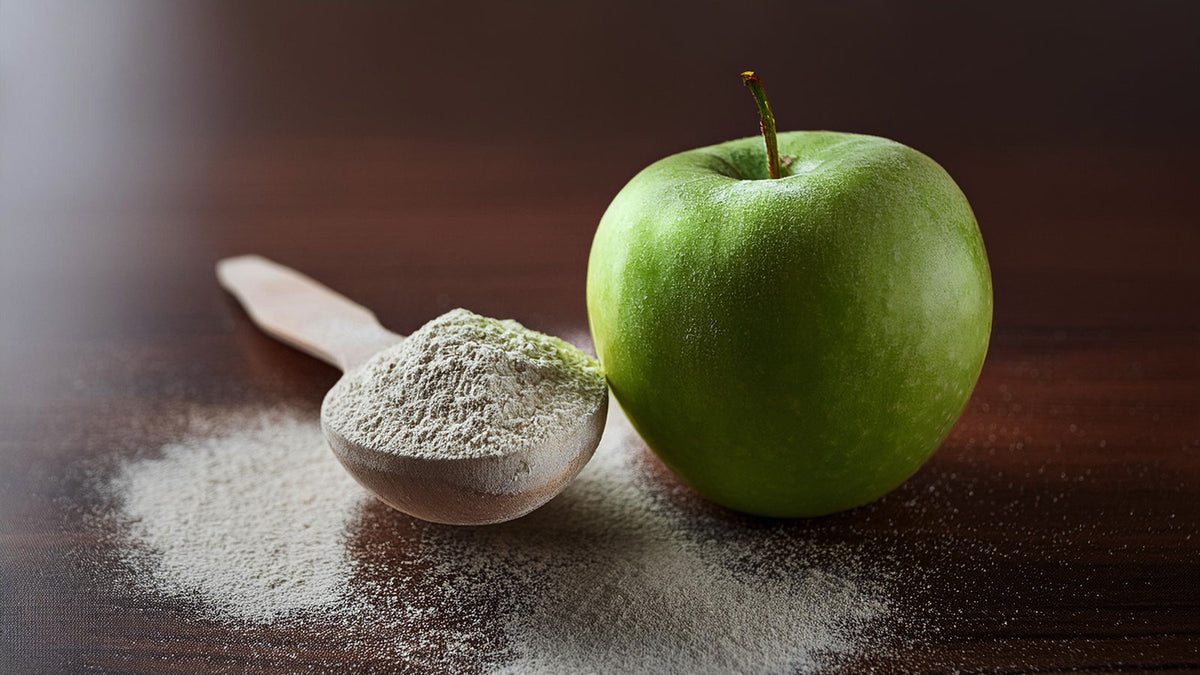 image of colostrum powder next to a green apple