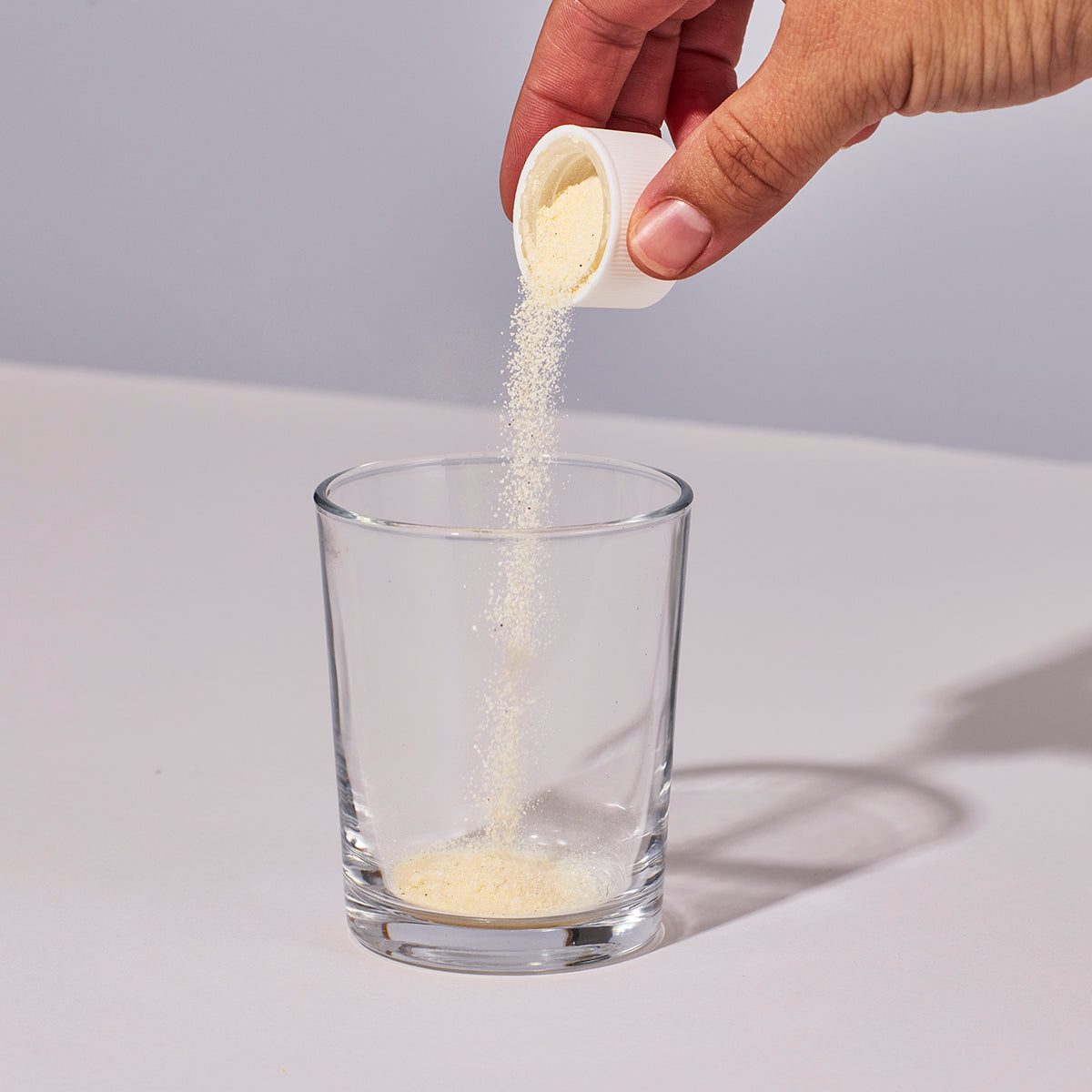 Image of person pouring a capful of Isotonix Prenatal Activated Multivitamin into a glass.